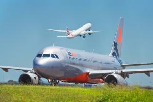 Sydney,Australia - February 13,2016: A Jetstar Airbus A320 taxies out to the runway as a Virgin Australia flight takes off ahead of it. Jetstar was created by QANTAS to compete with Virgin.