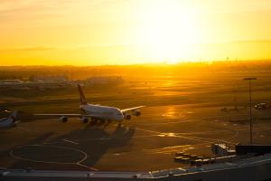 Sydney, Australia, November 8, 2014 World largest passenger aircraft Airbus A380 in Qantas colour scheme, is getting ready for take-off at Sydney (Kingsford Smith) Airport. Also visible some Commercial Airplanes parked, waiting for passengers to board. Also visible in the background a Sunrise glowing through the clouds